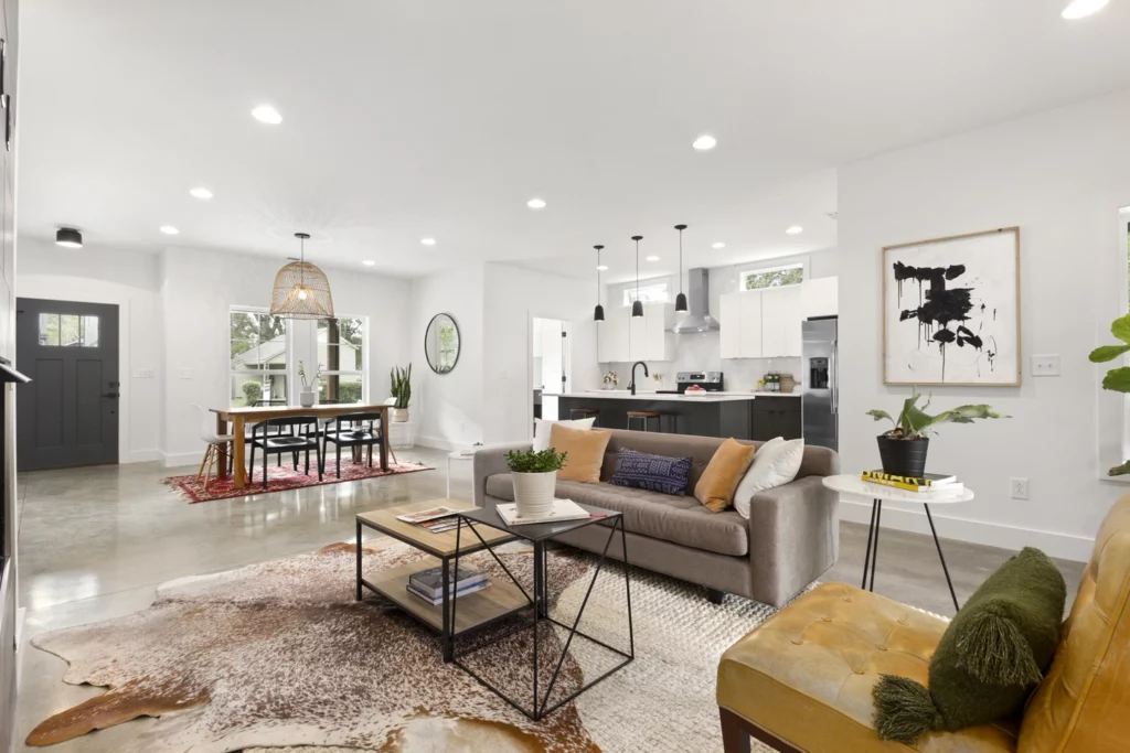 Custom home in Nashville with view of an open living room and kitchen with white upper and gray lower cabinets, an oversized island, range hood and full-height backsplash tile