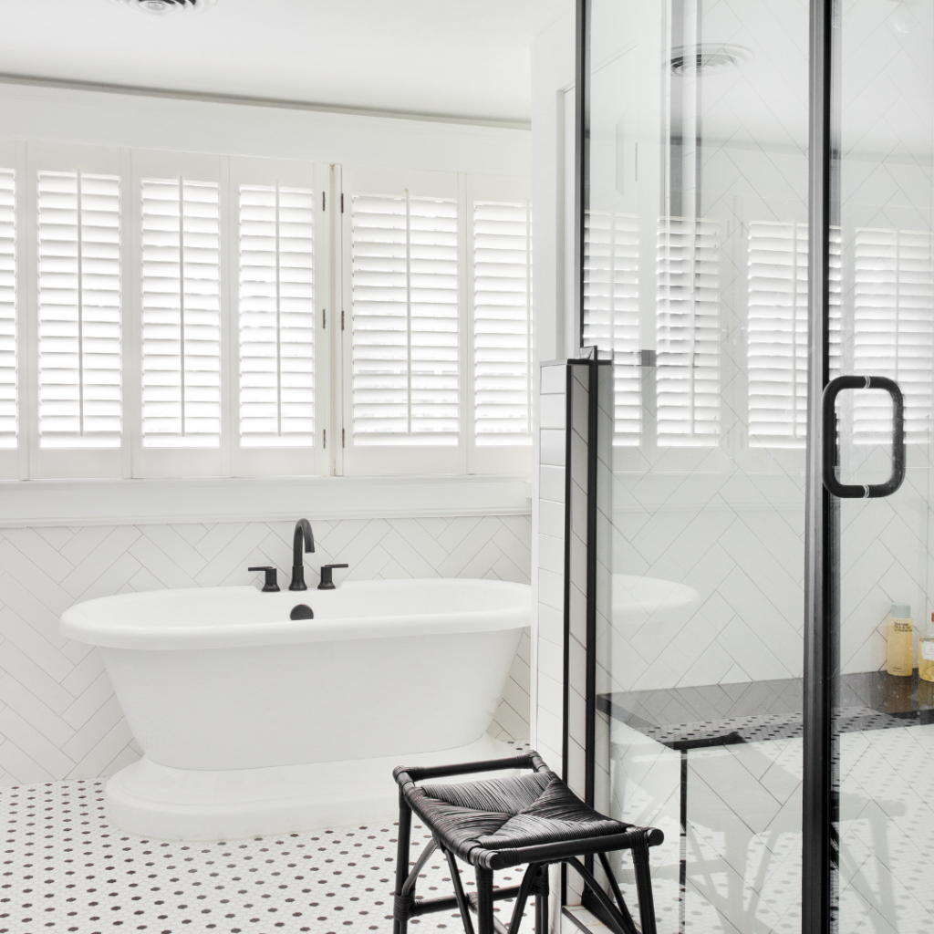 Modern white bathroom remodel with a freestanding tub, glass shower, and black fixtures.