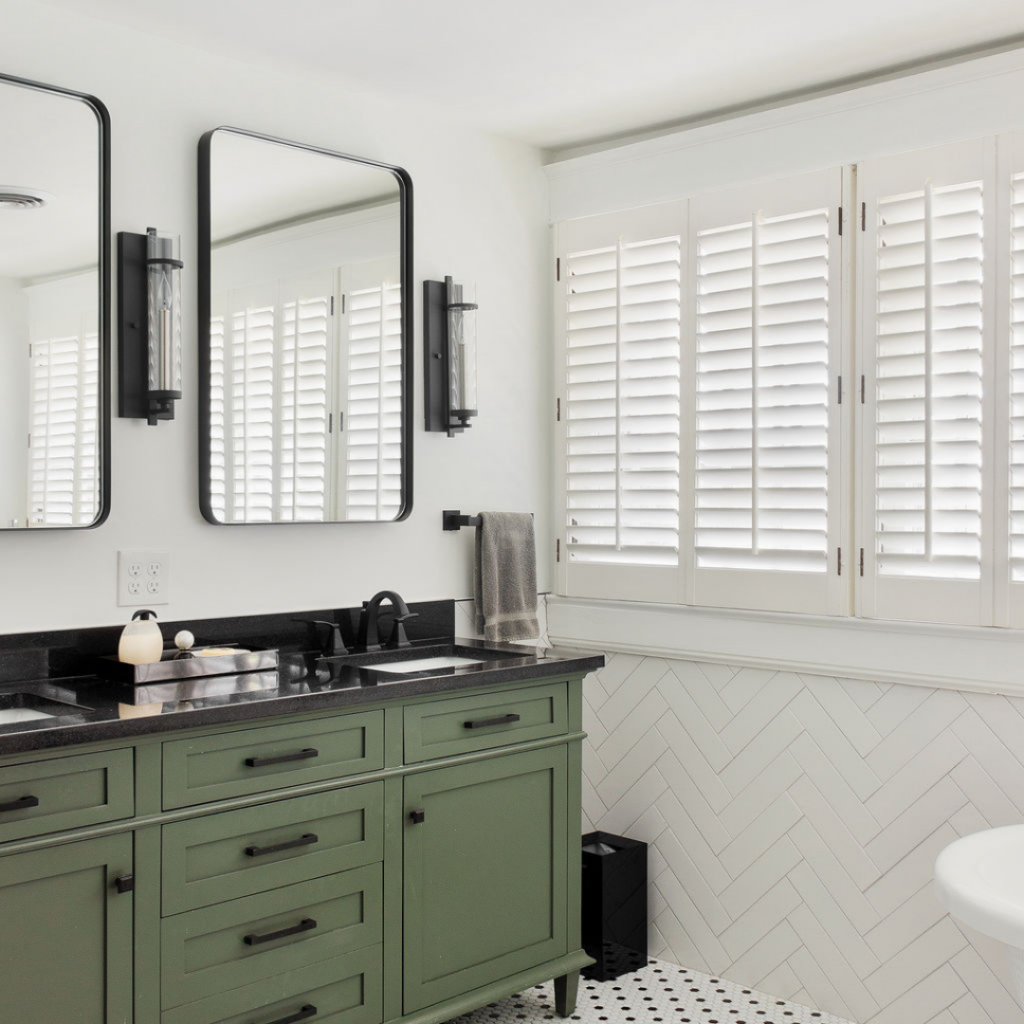 Modern bathroom remodel with green vanity, black countertops, and herringbone tile.
