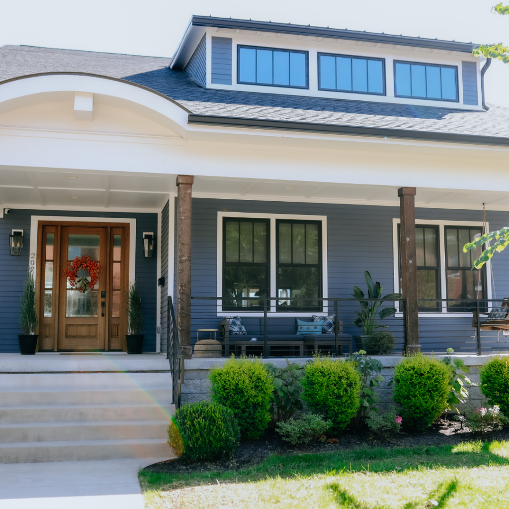 Modern Craftsman-style home with a spacious front porch and dark blue siding.