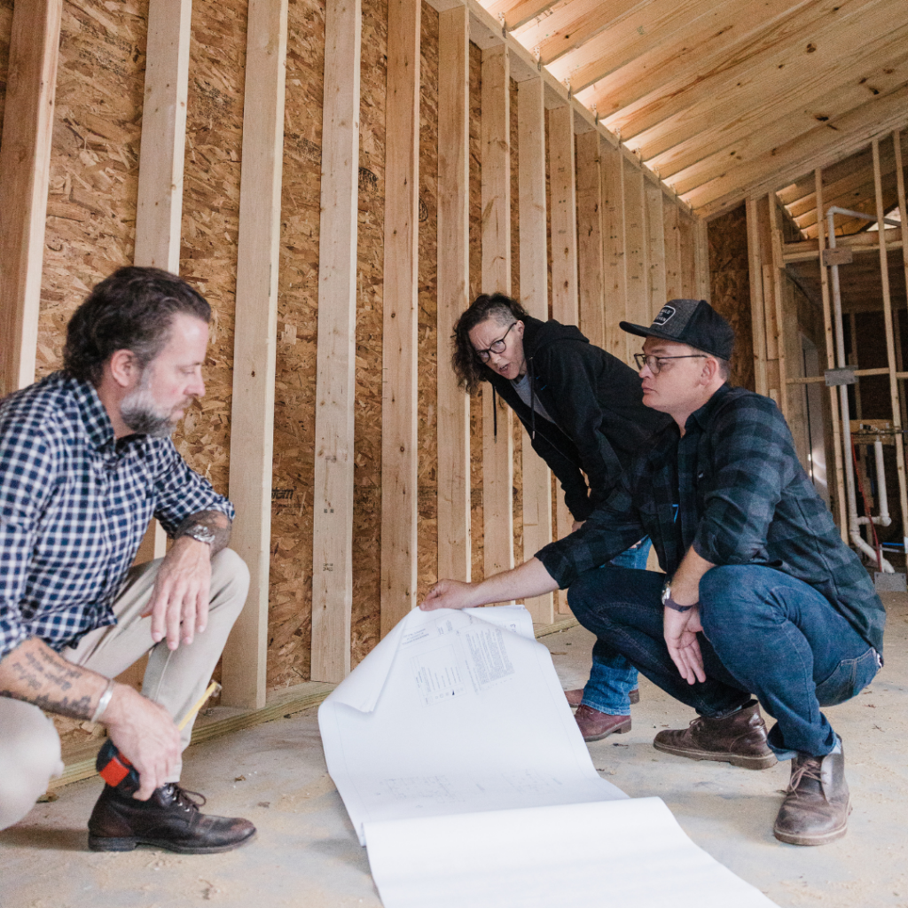 BuildCo7 team reviewing blueprints inside a home under construction.