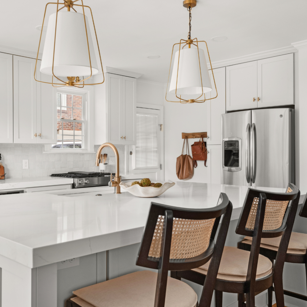 Bright white kitchen with gold accents, pendant lighting, and a large island.
