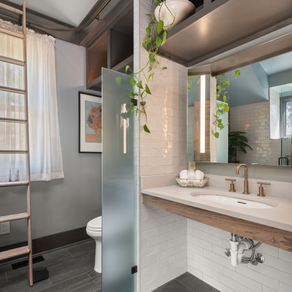 Modern bathroom remodel with floating vanity, gold fixtures, and frosted glass partition.
