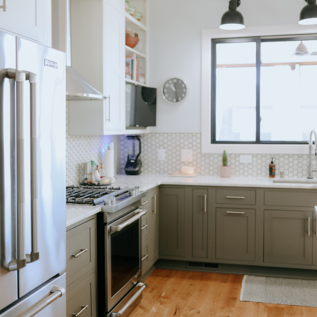 Contemporary kitchen with gray cabinets, hexagonal tile backsplash, and stainless steel appliances.