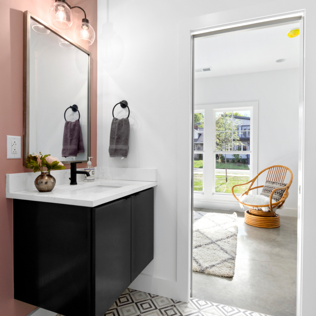 Modern bathroom with a black floating vanity, white countertop, and geometric tile flooring.