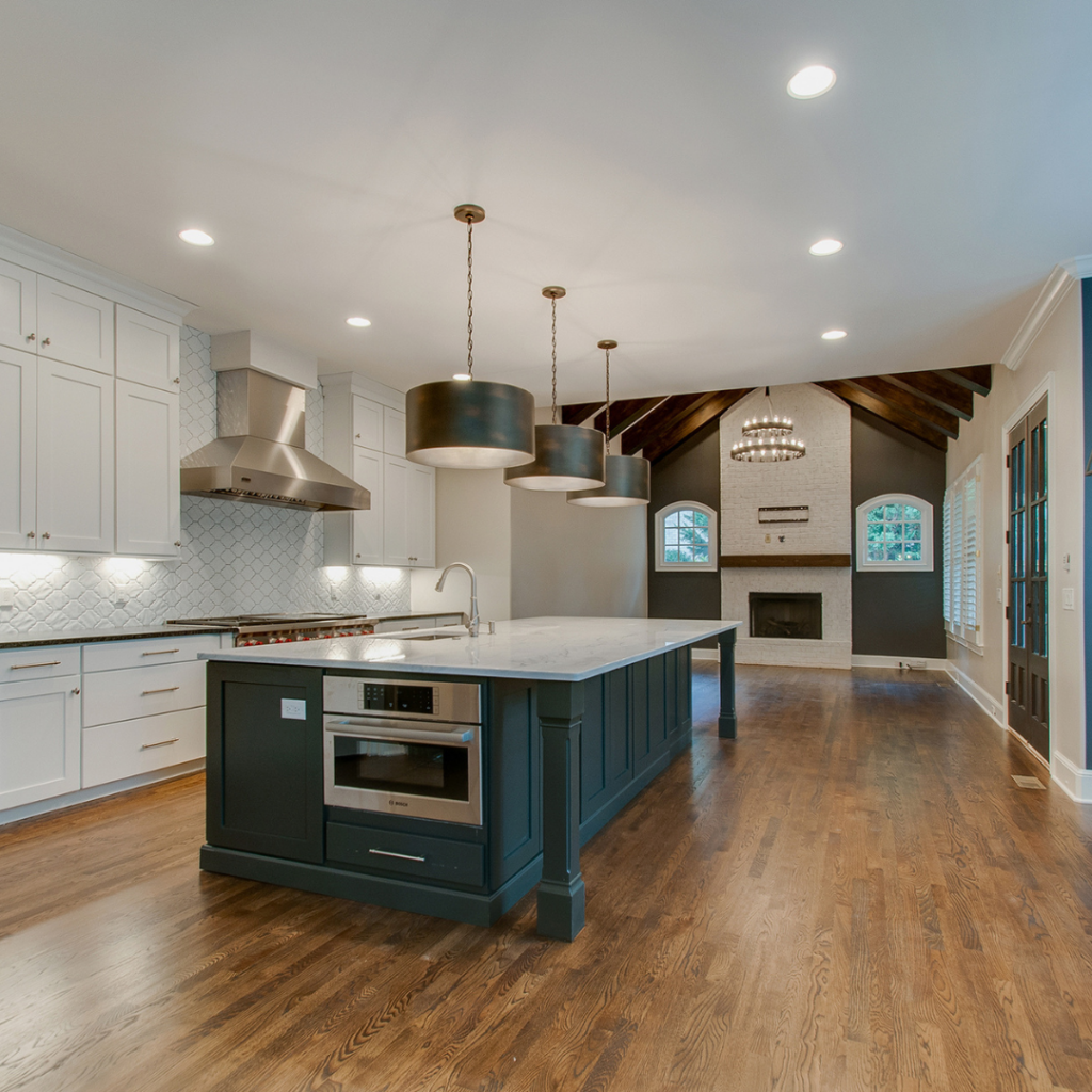 Open-concept kitchen with a dark blue island, white cabinets, and vaulted ceiling.
