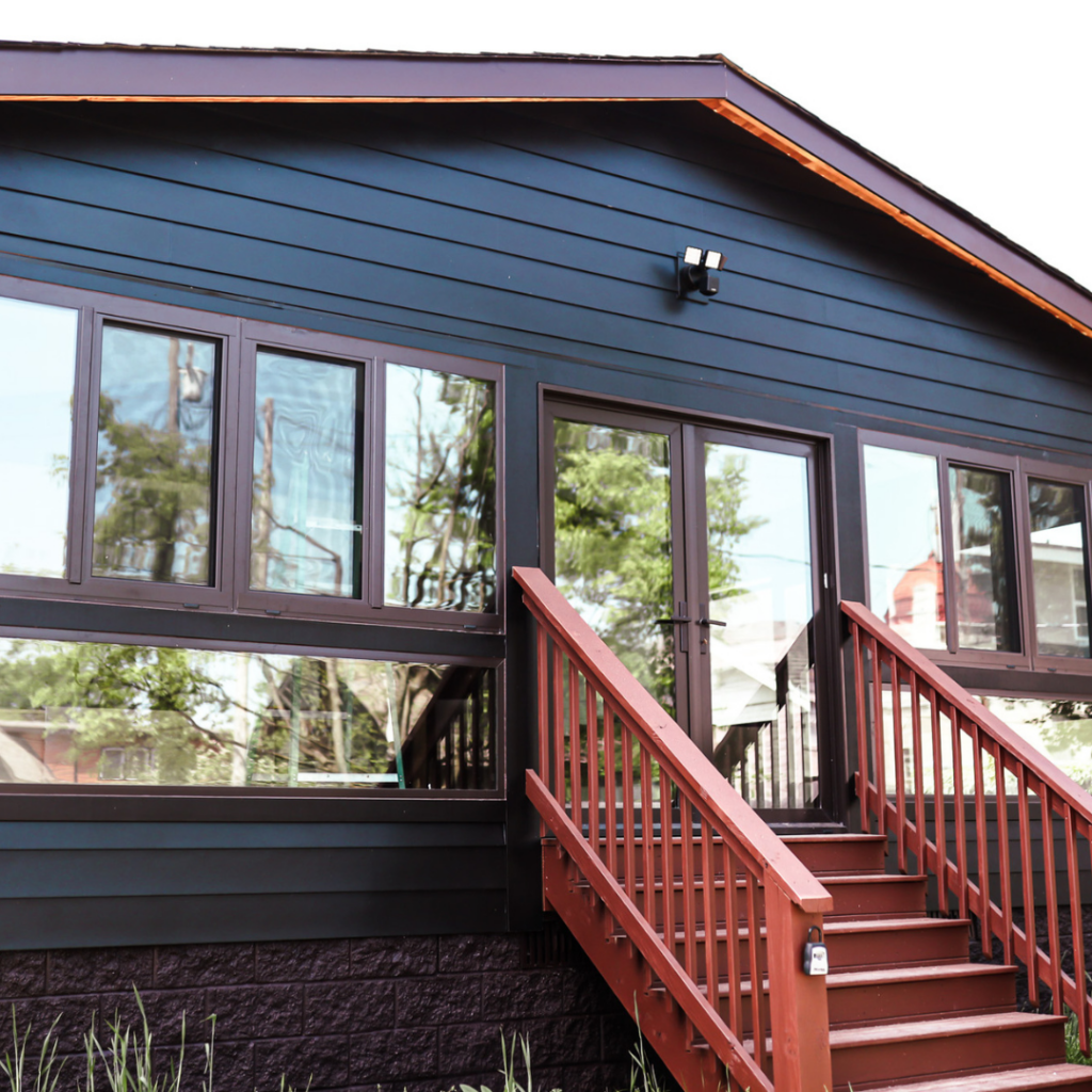 Dark blue home addition with large windows and wooden staircase.