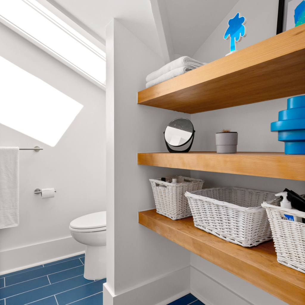 Modern bathroom remodel in Nashville, TN, featuring sleek floating wood shelves and blue tile flooring.