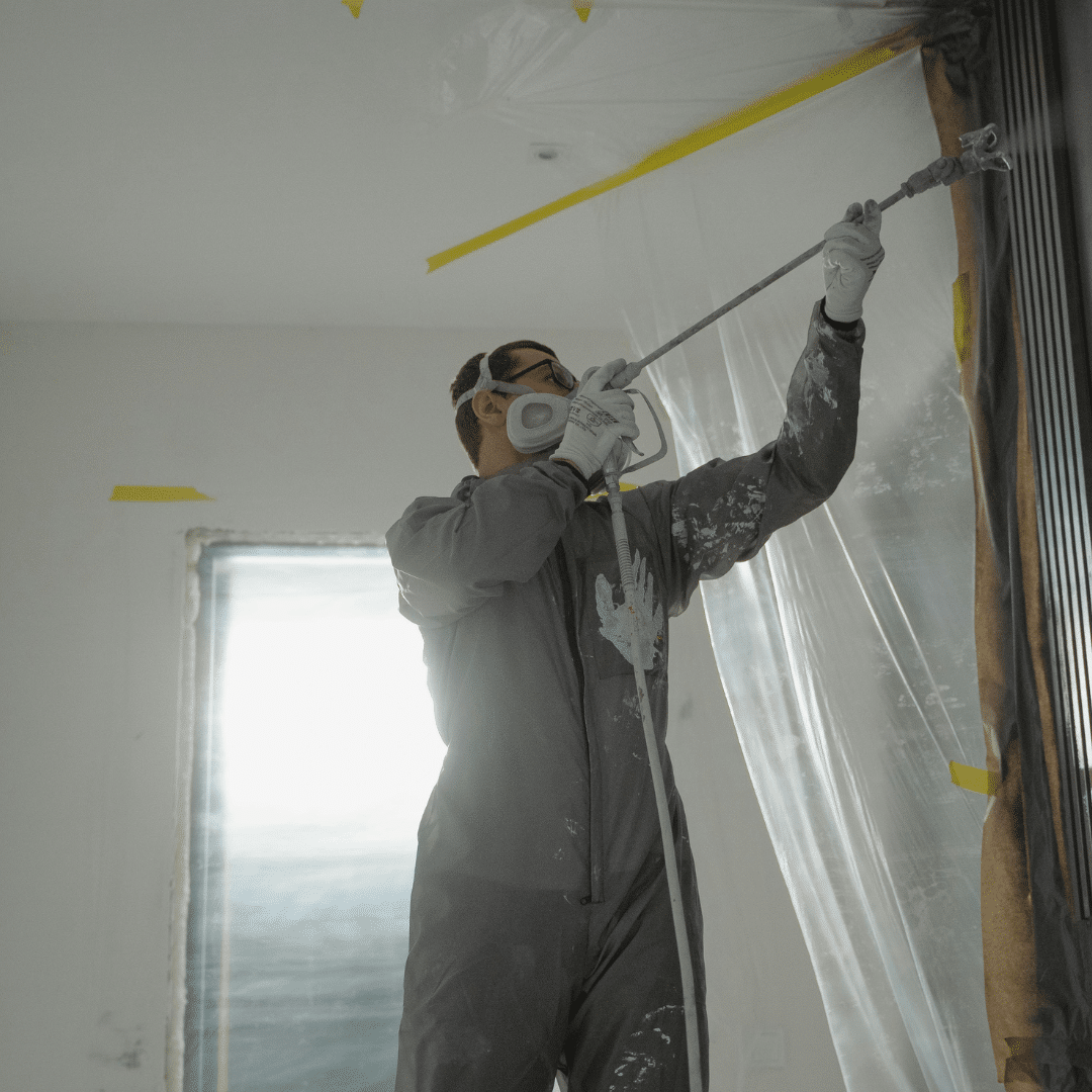 Professional home builder spray-painting interior walls during a custom home renovation in Nashville, TN.